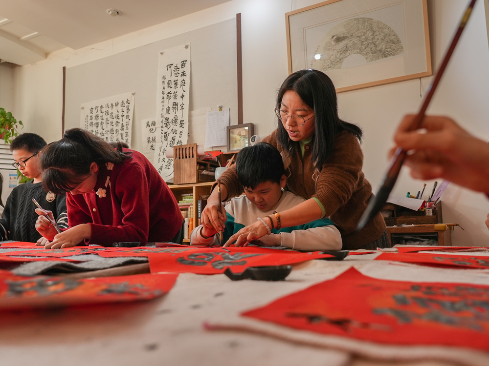文艺志愿者指导孩子写“福”字。刘一明摄