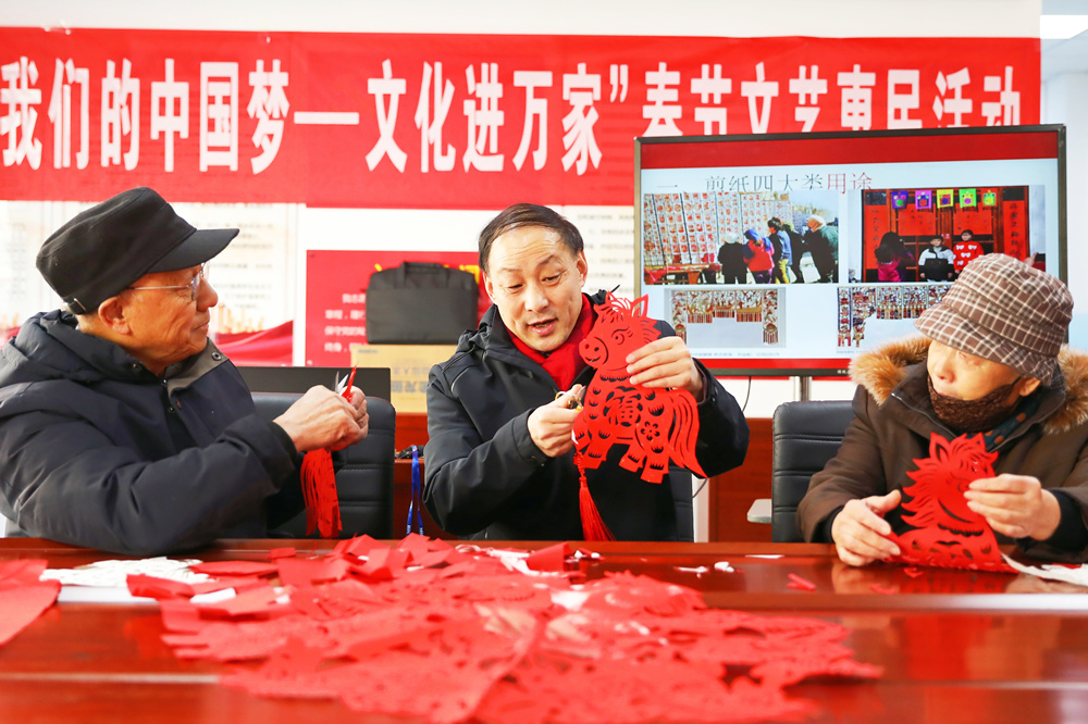 非物質文化遺產代表性傳承人向居民介紹剪紙作品《馬上有福》。岑屹攝