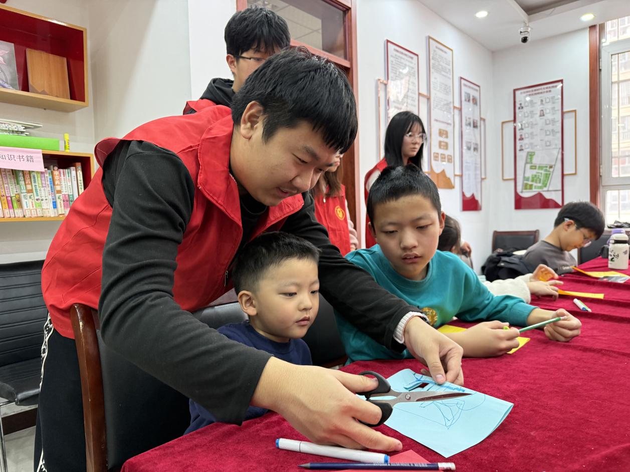 志愿者教孩子们剪纸。张子衡摄