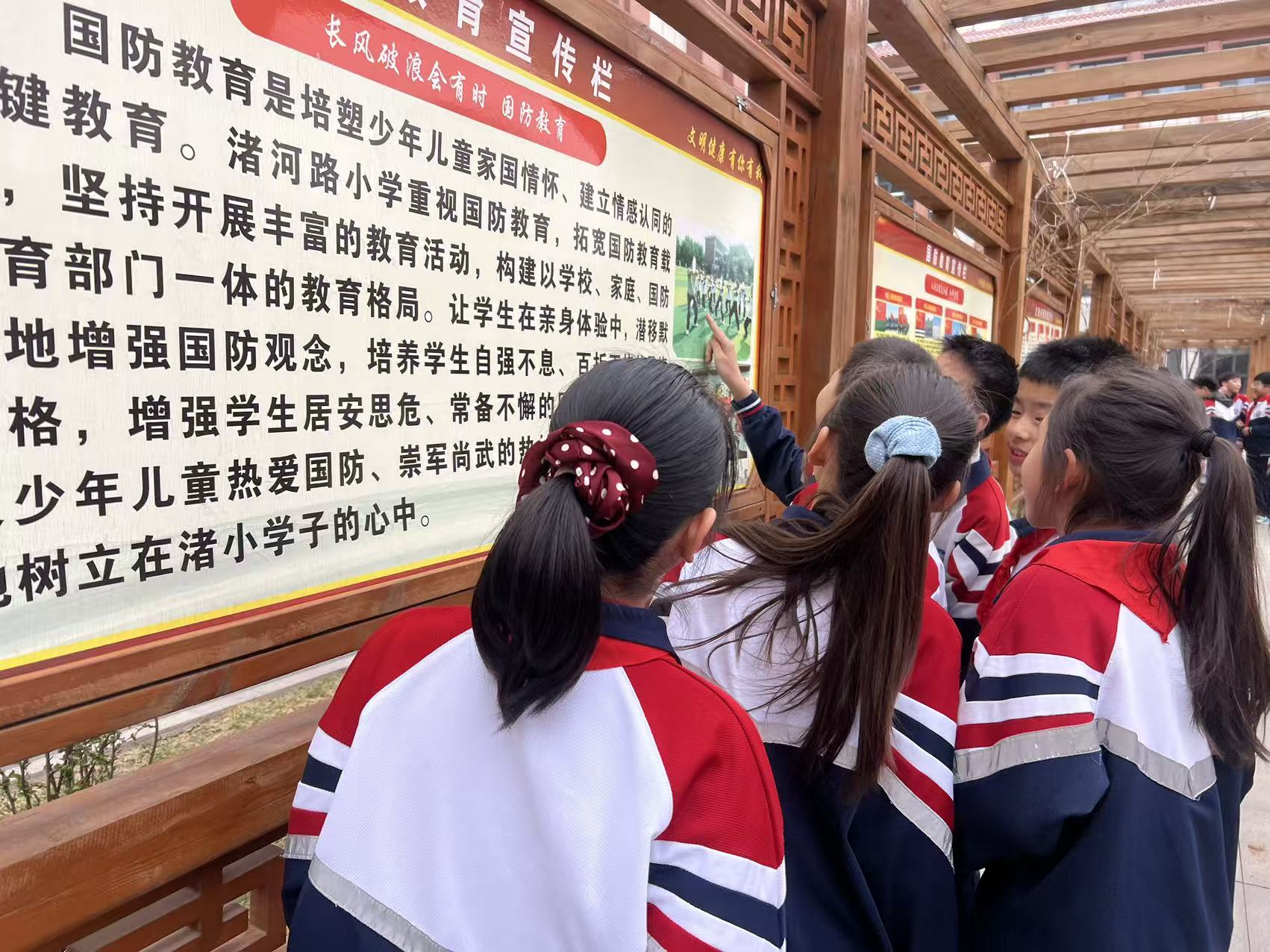 学生课间在国防教育长廊宣传栏前学习讨论。李子爽摄