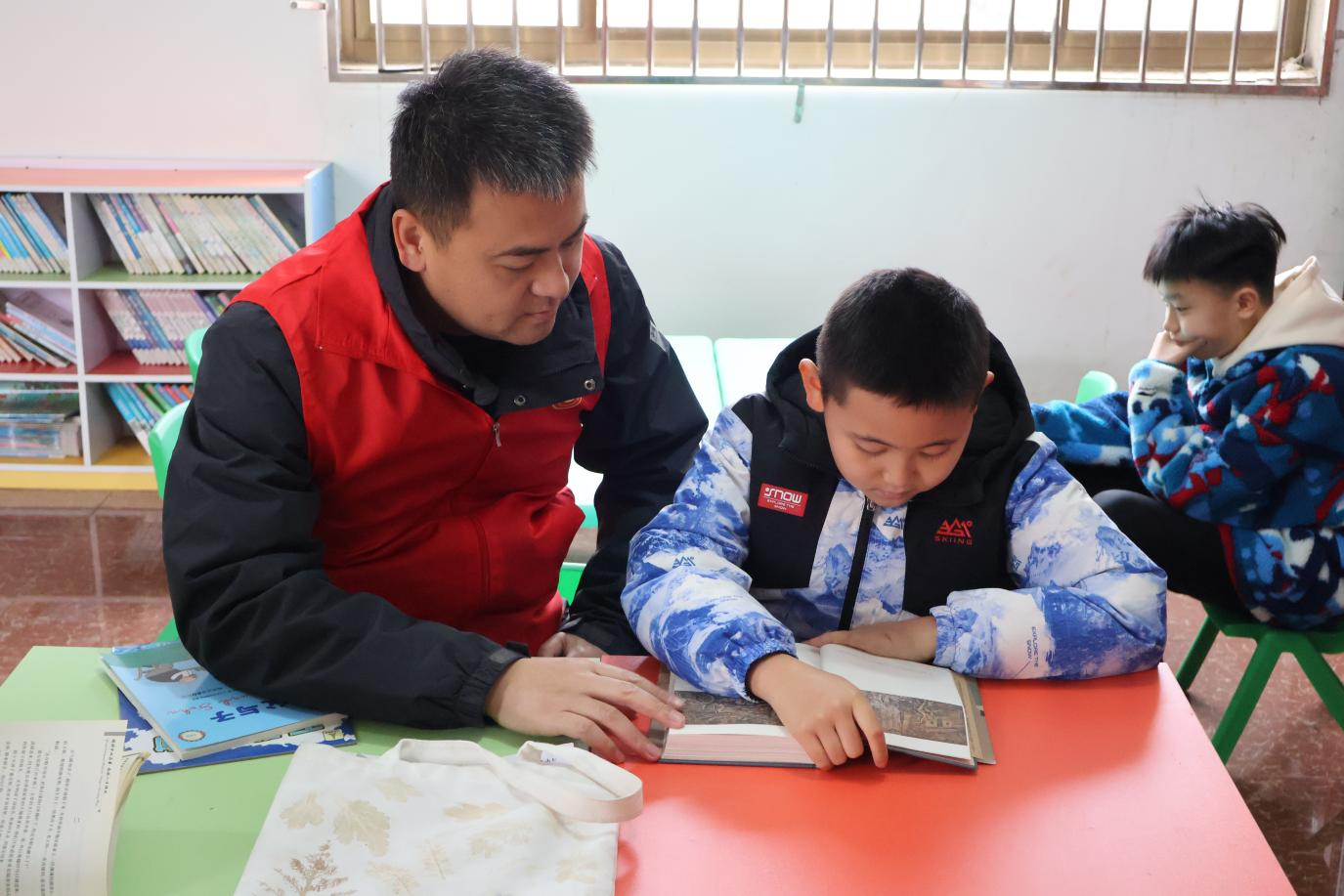 志愿者陪伴儿童阅读并进行答疑。莫赛城摄