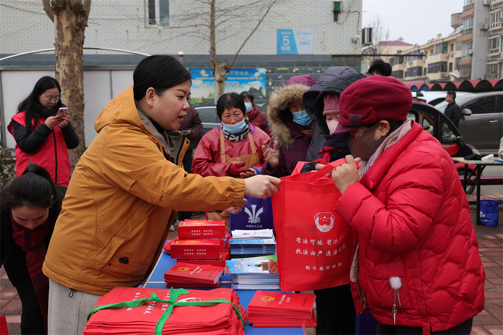 志愿者为居民发放普法宣传包。吴潇摄
