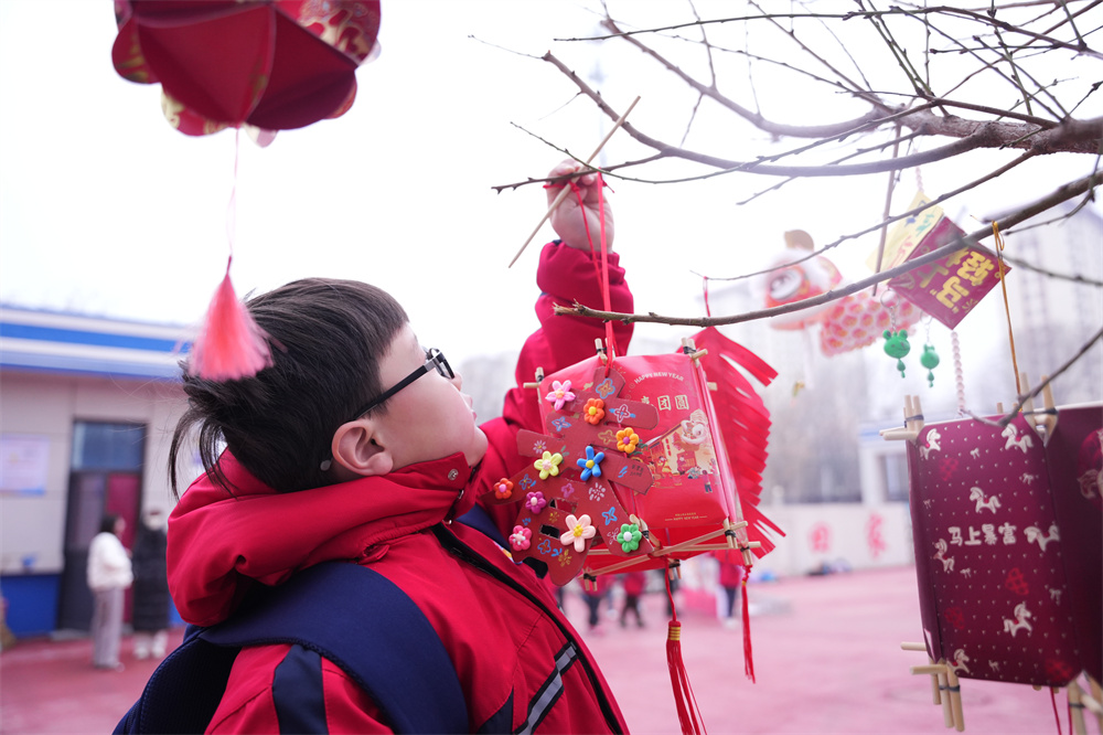 在河北省隆尧县第五实验小学,学生正在将春节主题作品悬挂在树上。郭泽鑫摄