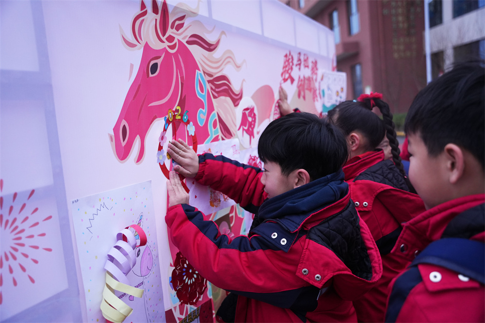 在河北省隆尧县第五实验小学,学生们正在“骏马驰骋 创造骐骥”主题幕布前粘贴创意剪纸。郭泽鑫摄
