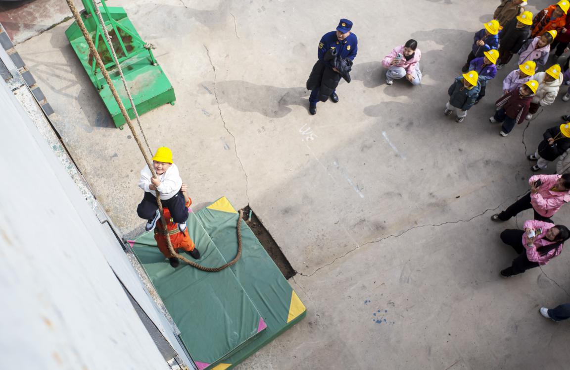 孩子们在消防员的保护下体验攀爬救援项目。聂长青摄