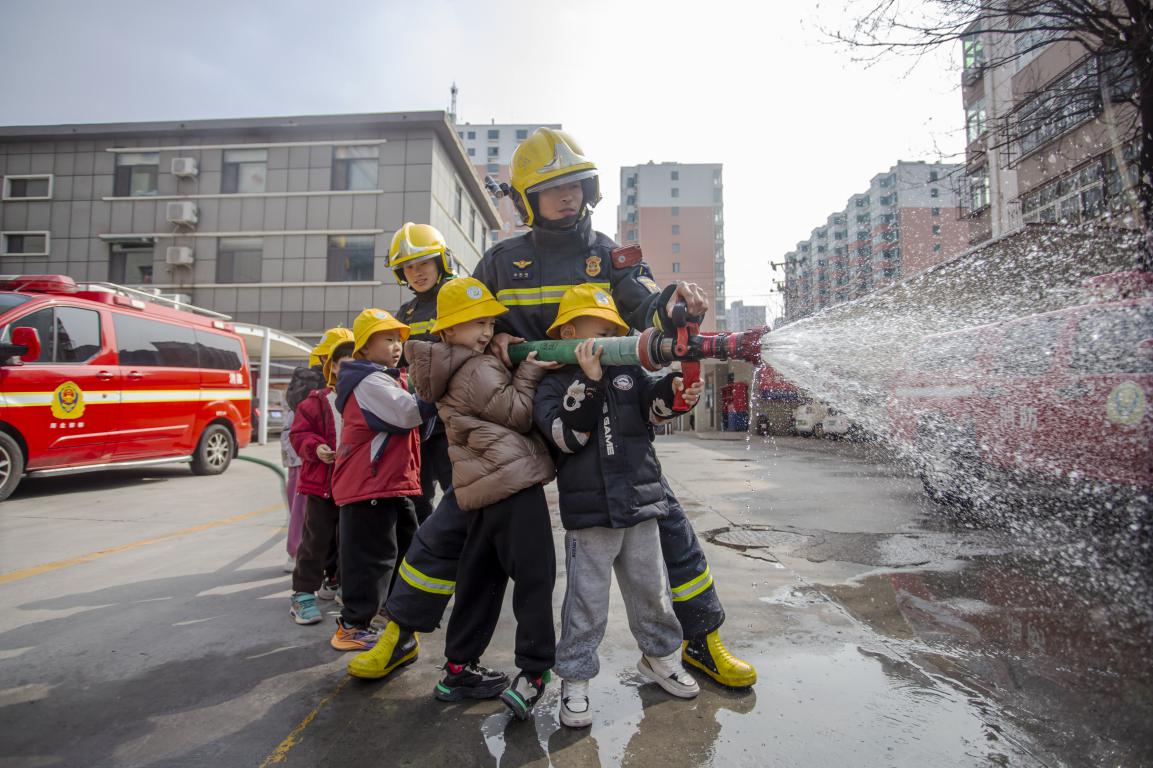 孩子们在消防员的指导下体验使用消防水枪。聂长青摄