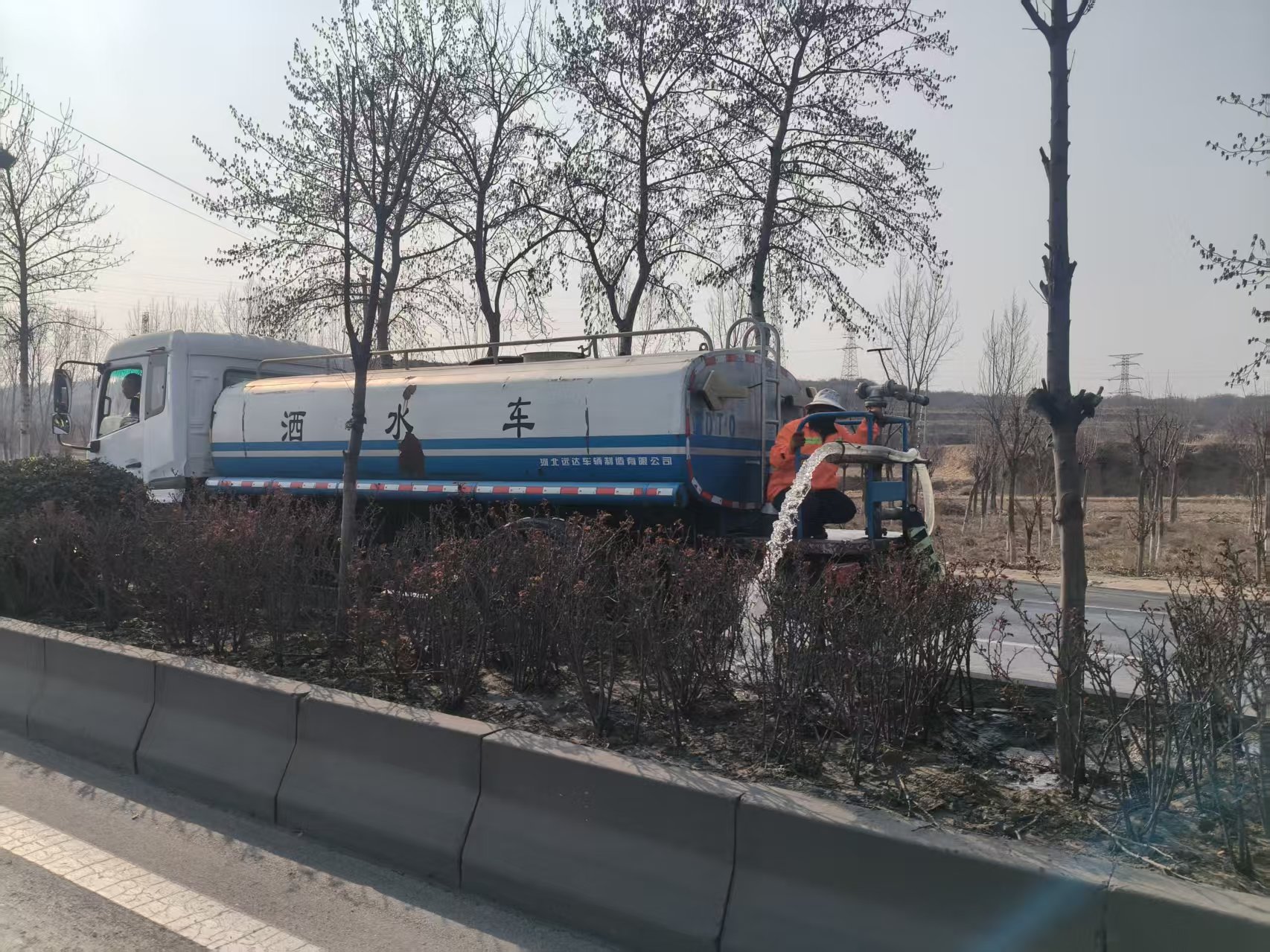 武安市交通运输局养护工人在邢峰线为树木浇灌返青水。郝彦旗摄