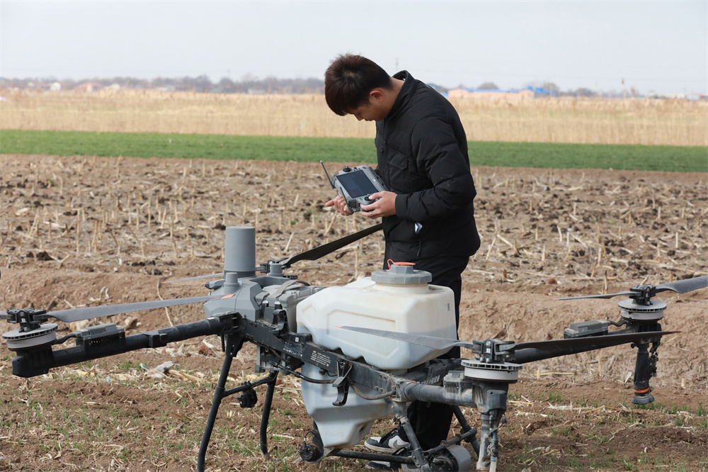 3月18日,农民在麦田间调试无人机。田博摄