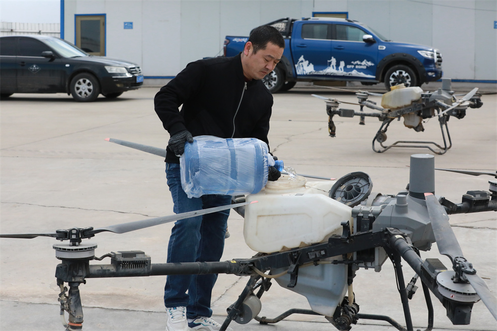 3月18日,农民正在给无人机加注叶面肥准备喷洒。田博摄