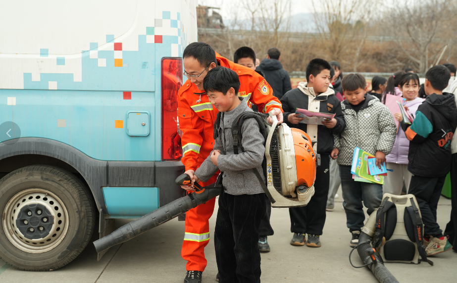 消防员正在带同学们体验专业背负式风力灭火机。张泽慧摄