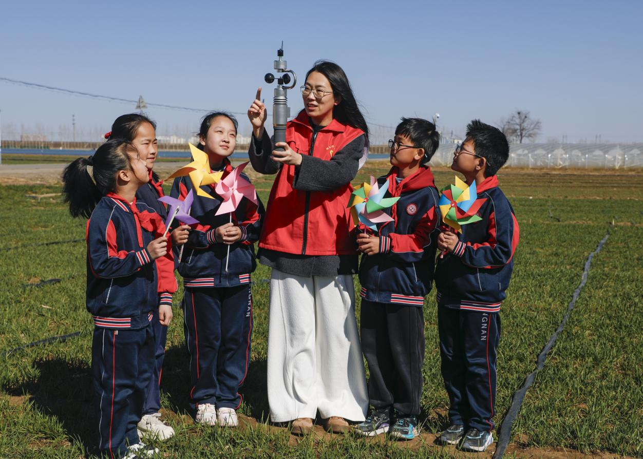 丰南区气象局的工作人员为四神庄小学的学生演示手持气象观测仪。陈军摄