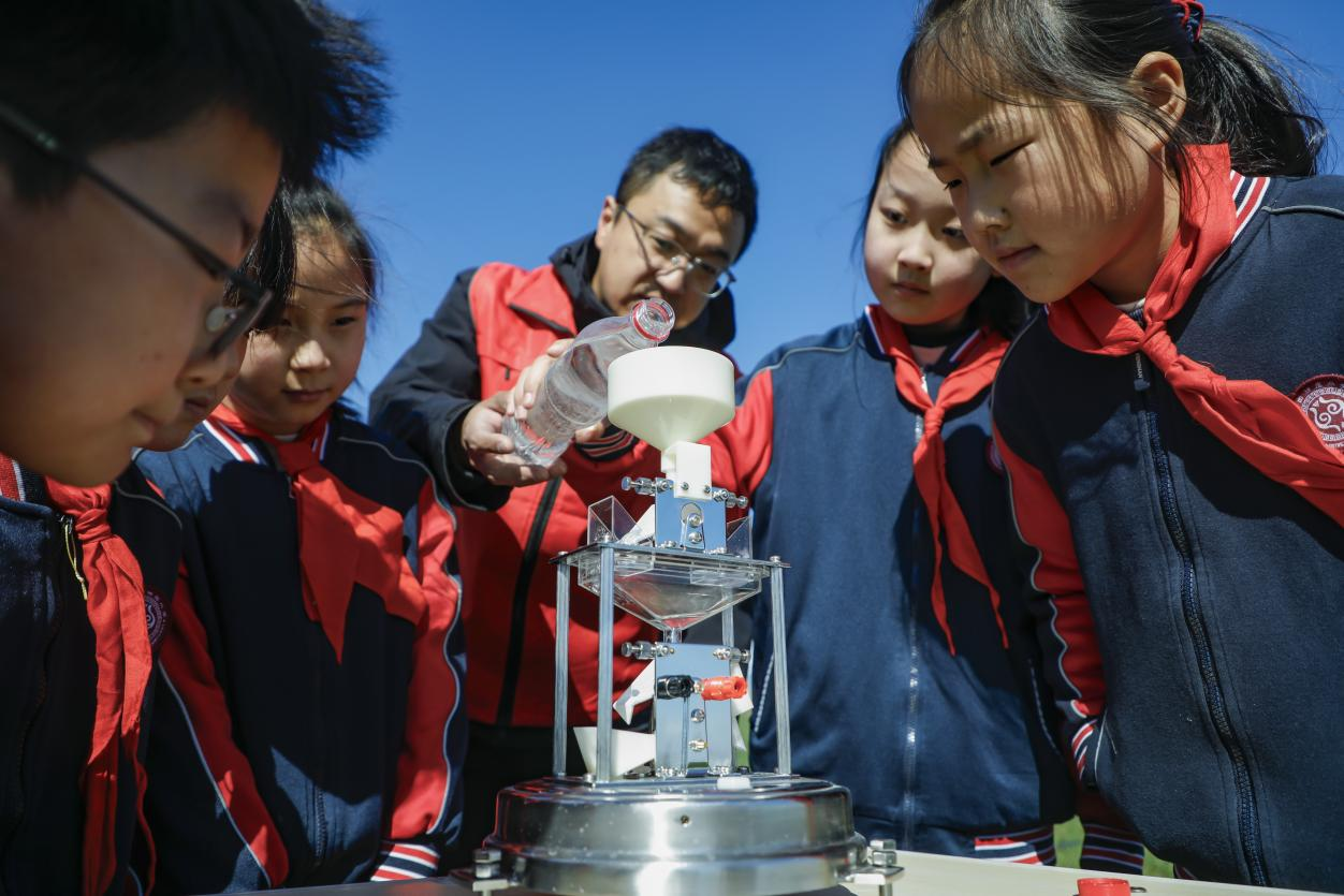 丰南区气象局的工作人员为四神庄小学的学生演示翻斗式雨量计。陈军摄