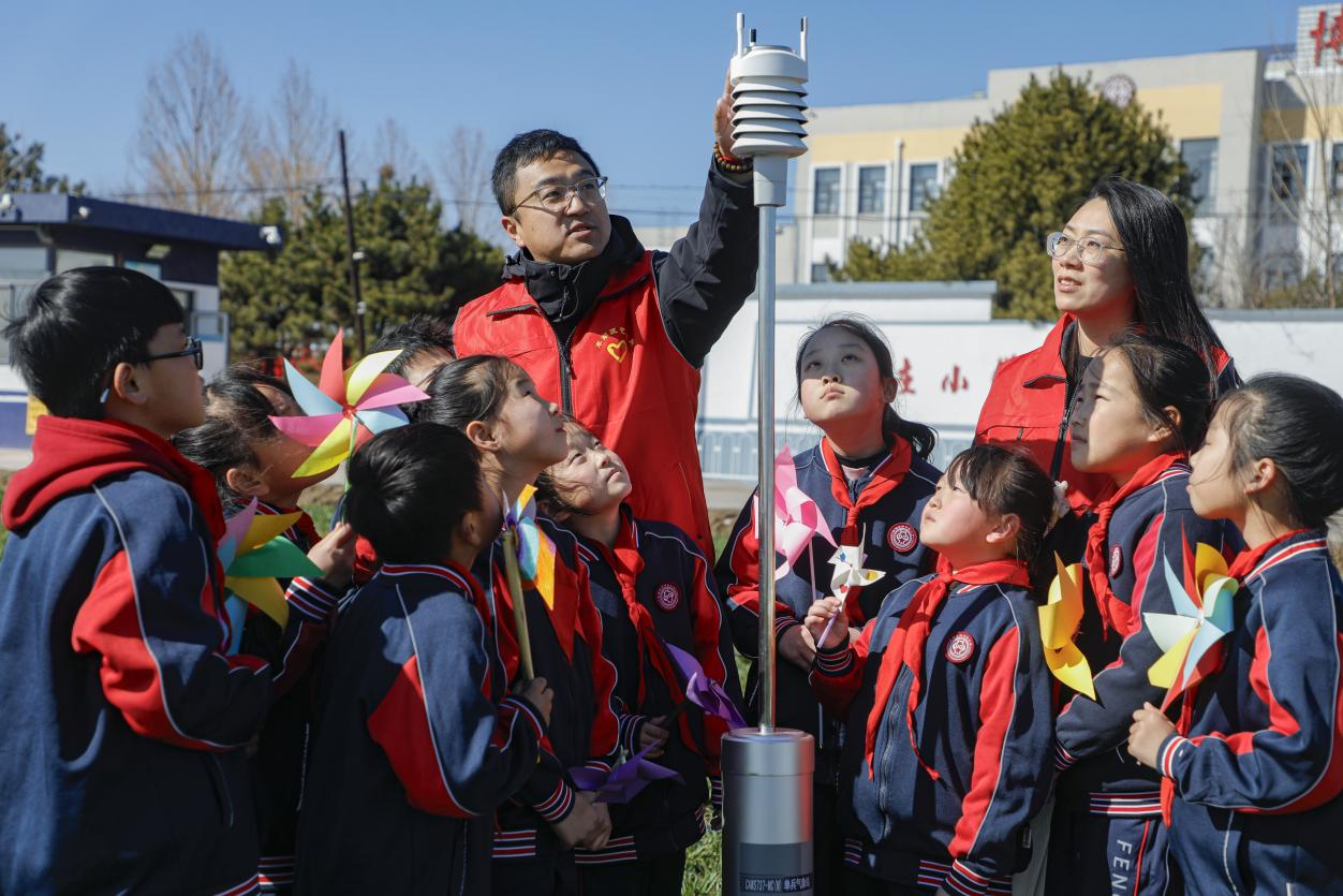 丰南区气象局的工作人员为四神庄小学的学生演示一体化传感器。陈军摄