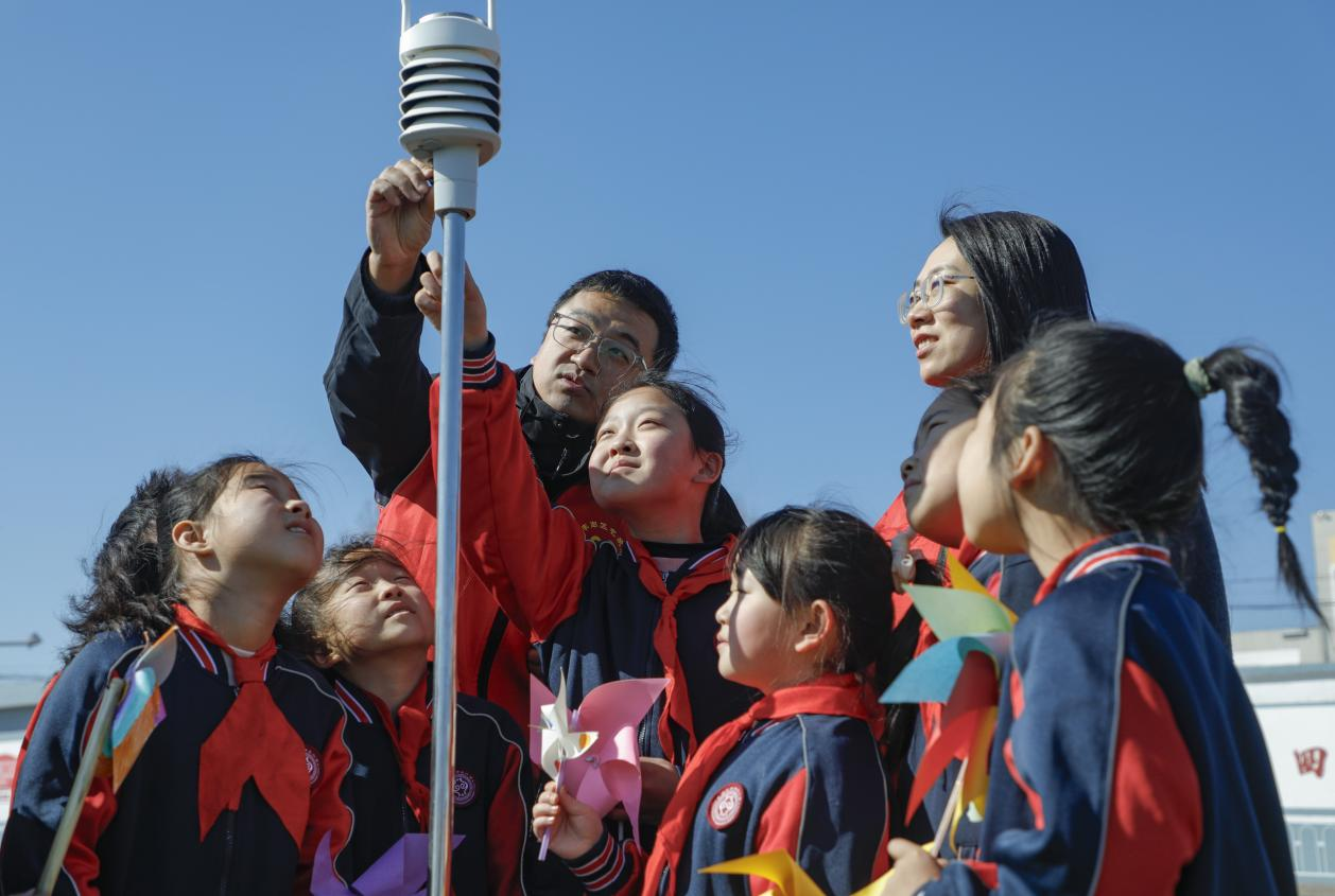 丰南区气象局的工作人员为四神庄小学的学生演示一体化传感器。陈军摄