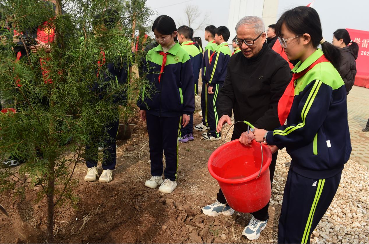 雷锋同班同学谢迪安与师生代表一同栽下象征雷锋精神的常青树。傅新春摄