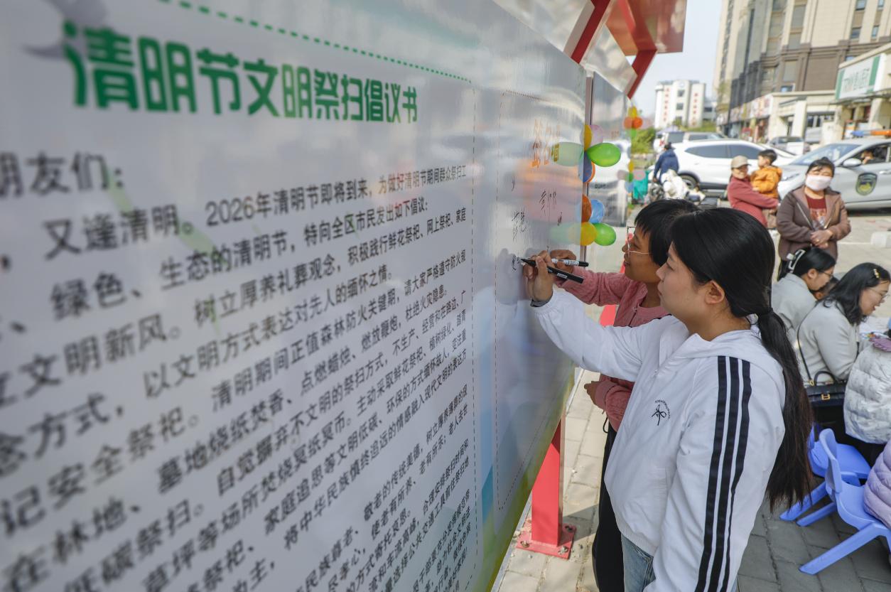 锦绣天城社区居民在文明祭扫倡议书上签字。陈军摄