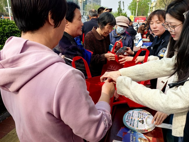 活动现场，群众领取兑换宣传册、环保袋等纪念品。赵明乾摄