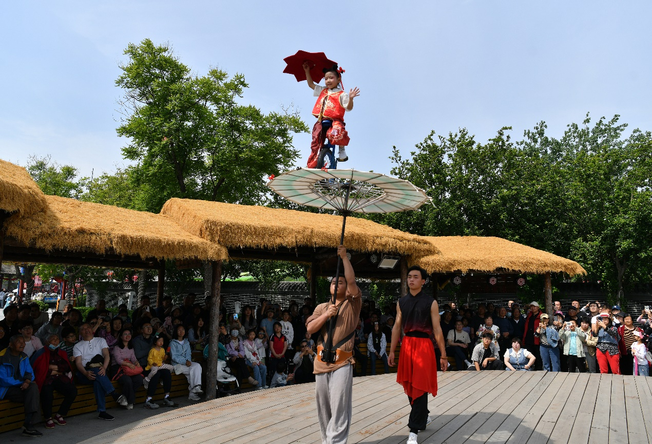 5月1日，杂技艺人在吴桥杂技大世界江湖文化城为游客表演《伞上单车》。苑立伟摄