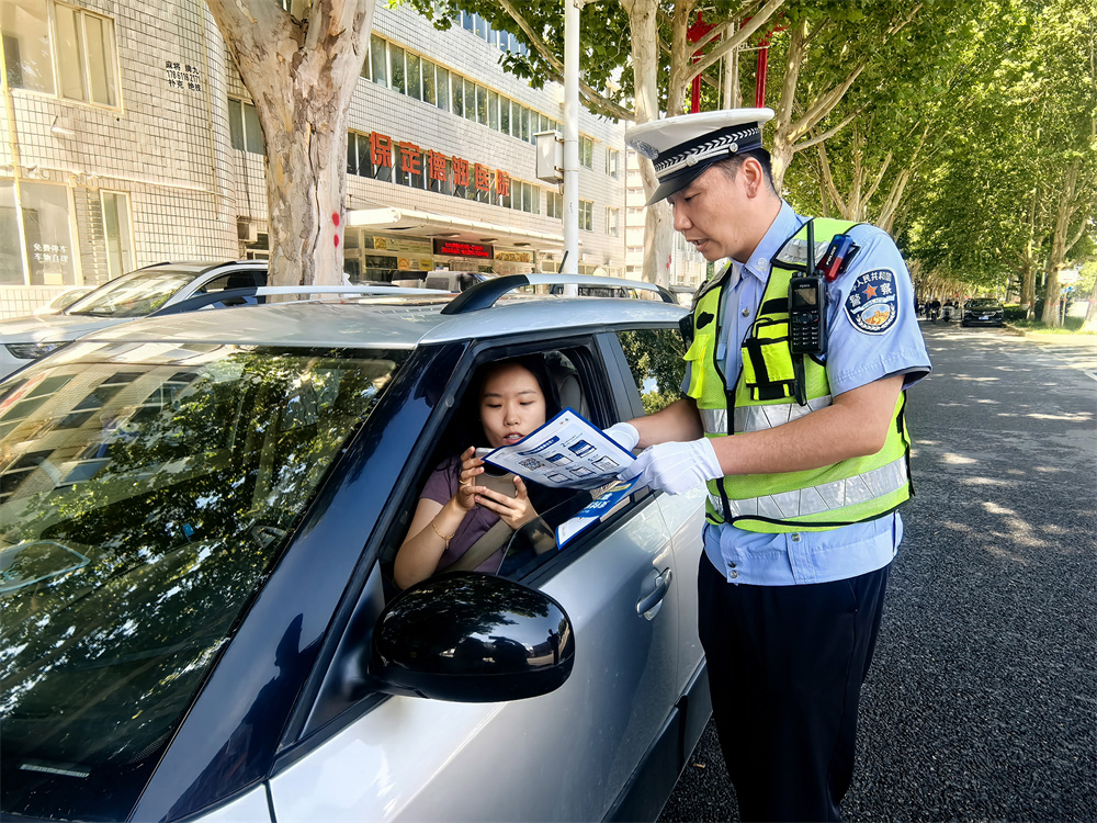 交警向机动车驾驶人传递低碳出行倡议。王杜超摄