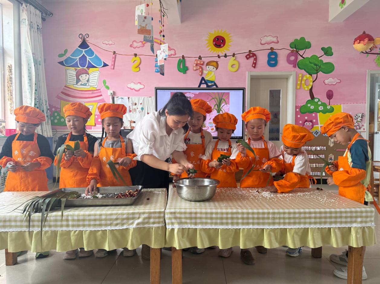毕家瞿阝幼儿园的小朋友和老师一起包粽子。佟苏美摄