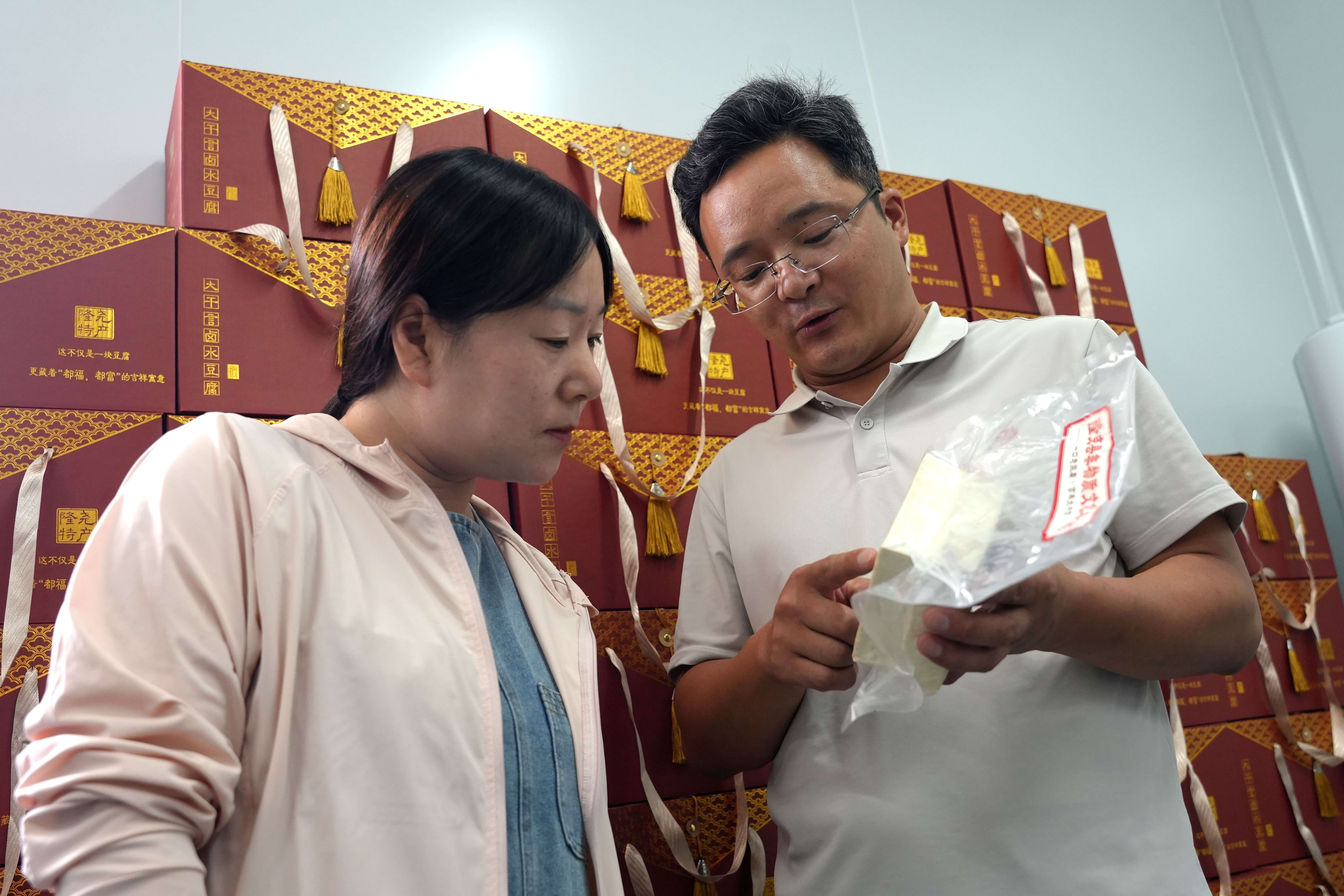 7月7日，在河北省隆尧县东良镇大干言村联村共建豆腐加工厂，公司负责人正在向顾客介绍大干言豆腐。王雪摄