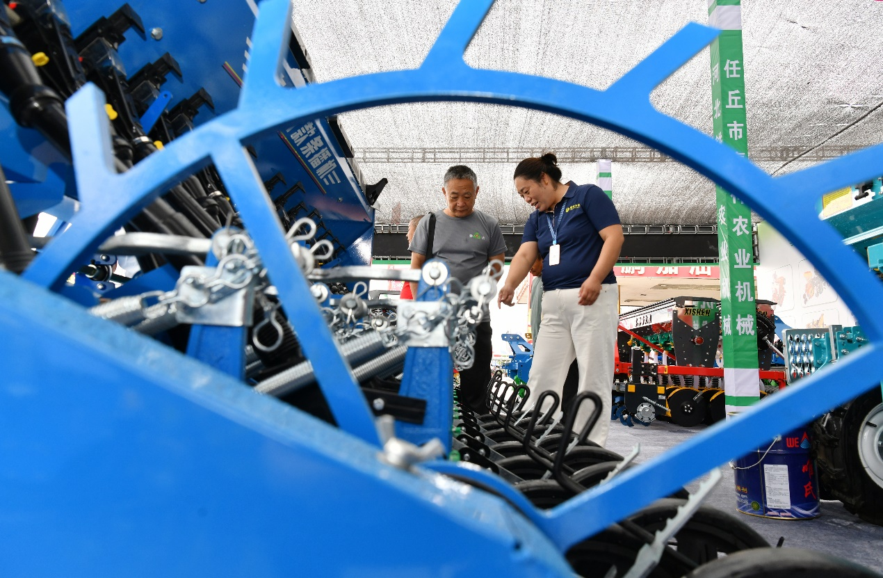7月17日，工作人员（右一）在阁辛庄村农机具推介活动中向客商推介农机产品。苑立伟摄