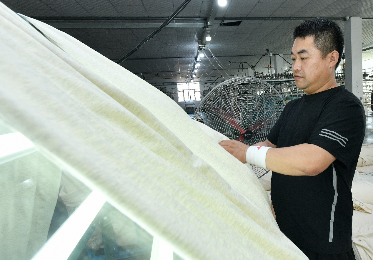 7月23日，工人在肃宁县一家针纺企业生产车间进行验布工作。苑立伟摄