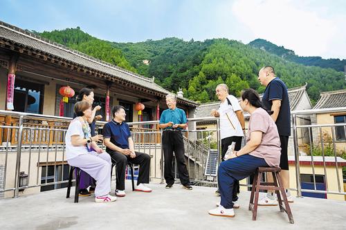 7月29日，孫振澤（左四）在自家民宿向游客介紹駱駝灣村的變化。本報記者 張 昊攝