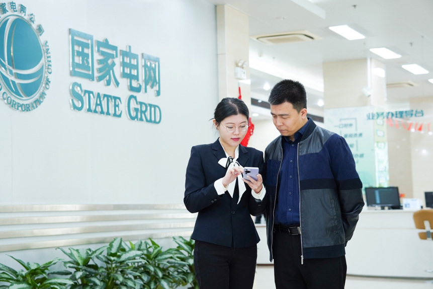 国网石家庄供电公司中心营业厅工作人员应用数智购电管家向客户讲解市场交易与政策。李晶摄
