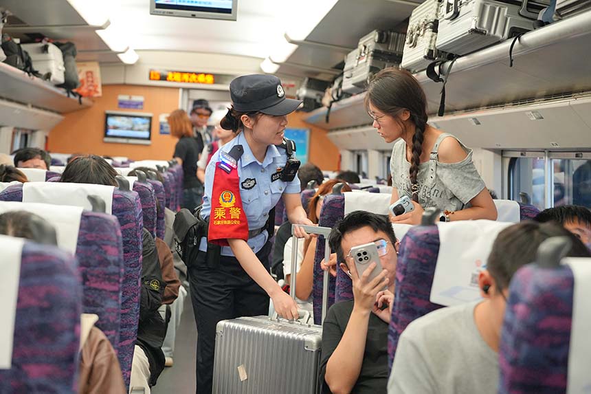 高铁车厢内，乘警协助旅客安置大件行李，引导旅客有序入座。贾义涵摄