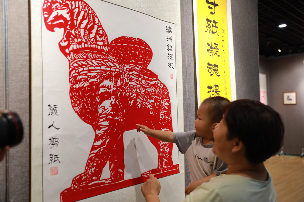 9月29日，祖孫兩人在滄縣非遺剪紙版權作品展上欣賞剪紙作品。   田博攝