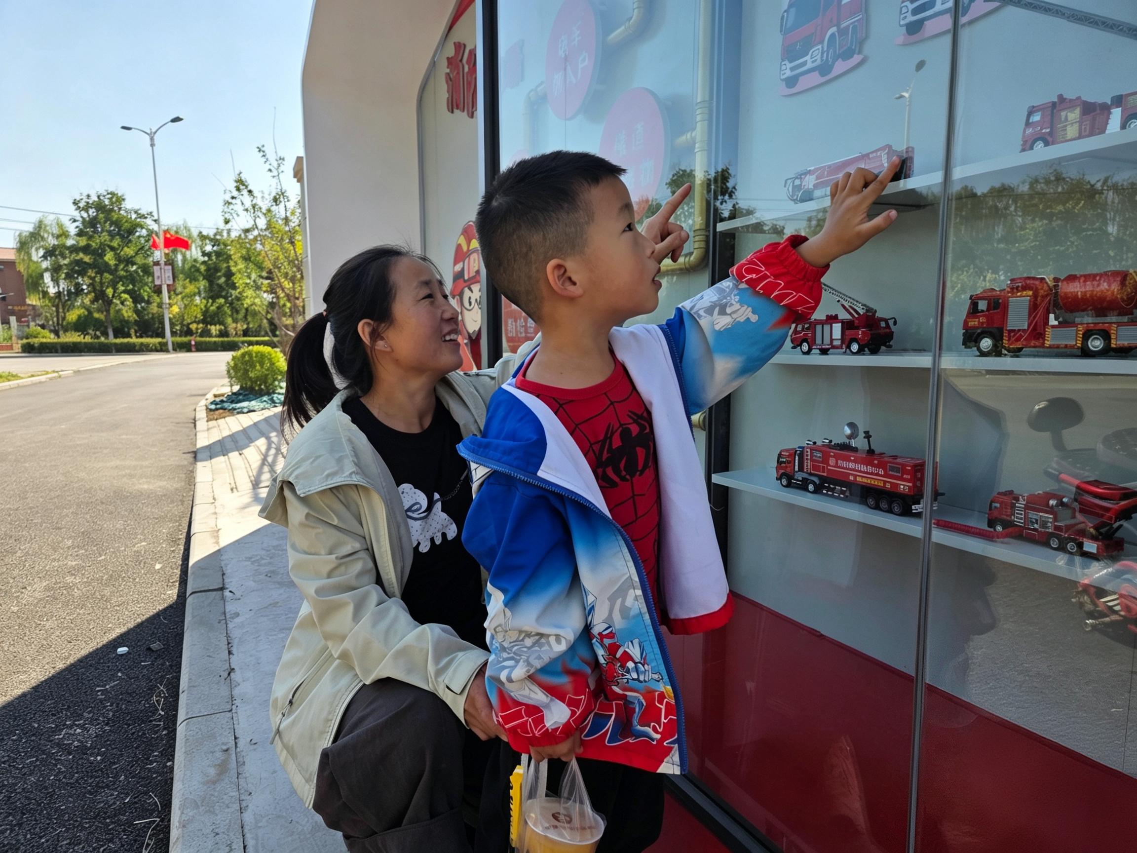 群众驻足观看消防宣传橱窗内消防车模型，近距离学习消防知识。徐亚乾摄