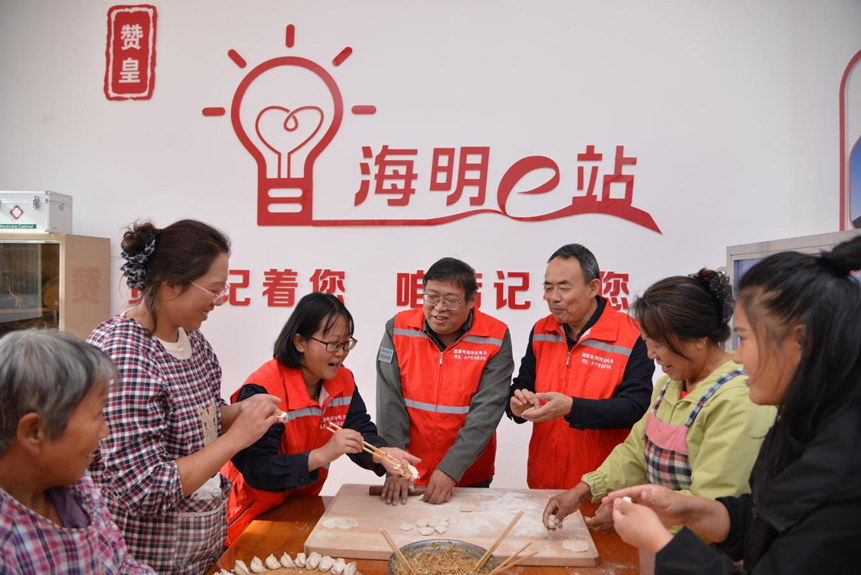 国网赞皇县供电公司“海明e站”志愿服务者为与松会村村民一起包饺子。卜志斌摄